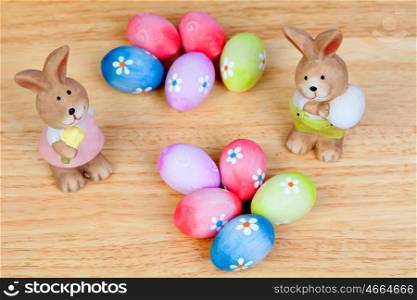 Funny rabbits ceramic with Easter eggs decorated with daisies on wooden background