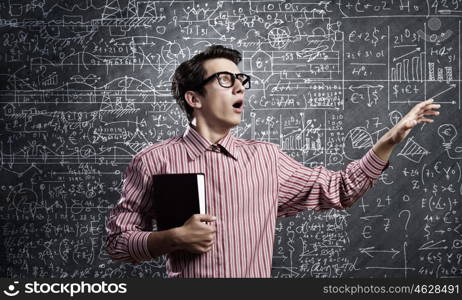 Funny scientist. Young funny man in glasses against chalk blackboard