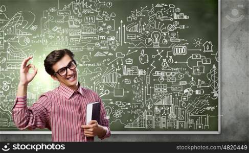 Funny scientist. Young funny man in glasses against chalk blackboard