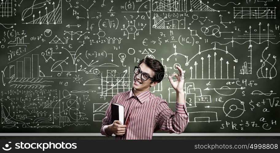 Funny scientist. Young funny man in glasses against chalk blackboard