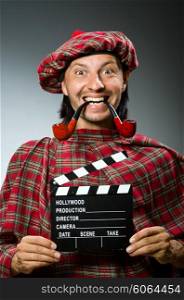 Funny scotsman with movie board and smoking pipe