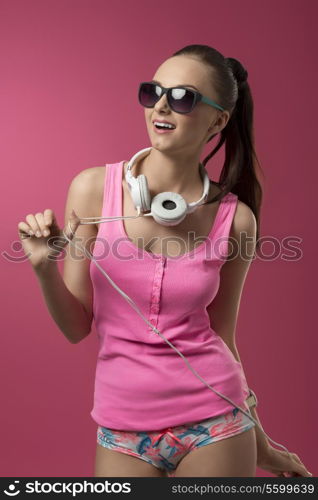 funny sexy girl with pink singlet, panties and sunglasses listening music with headphones