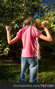 Funny shot of young girl hanging on clothesline at garden