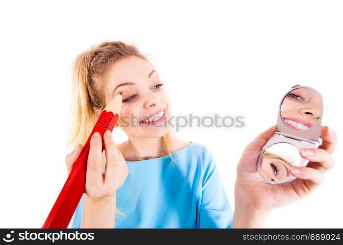 Funny silly woman trying to paint her eyebrows using big huge oversized regular student pencil. Make up fun concept.. Woman painting eyebrows using regular pencil