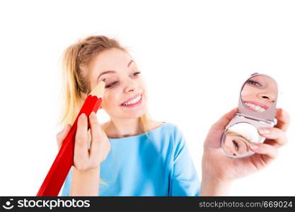 Funny silly woman trying to paint her eyebrows using big huge oversized regular student pencil. Make up fun concept.. Woman painting eyebrows using regular pencil