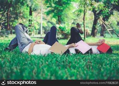 Funny students sleeping with books covering their face. Lazy and relaxation concept.