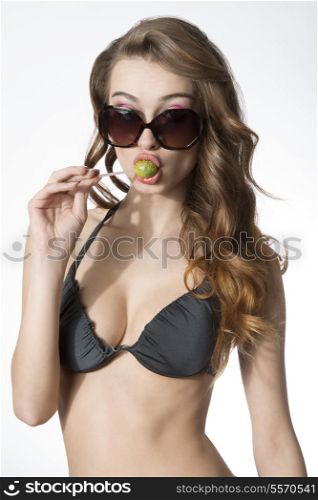 funny summer woman with sexy bikini, sunglasses and long hair eating lollipop