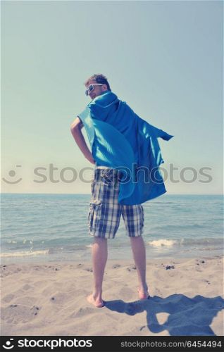 funny superhero standin at beach on hot sand