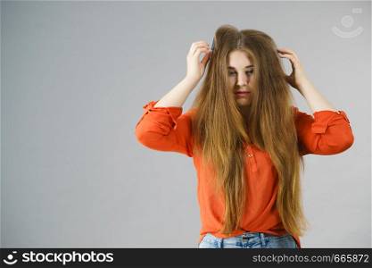 Funny teenage woman having problem with tangled tousled hair. Haircare problems concept.. Woman having tangled hair