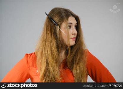 Funny teenage woman having problem with tangled tousled hair. Haircare problems concept.. Woman having tangled hair