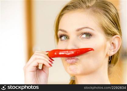 Funny woman holding red chilli hot pepper paprika pretending its moustaches. Spicy food, oriental seasonings concept.. Woman holding chilli hot pepper