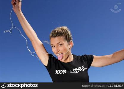 Funny woman listening to music outdoors through digital player
