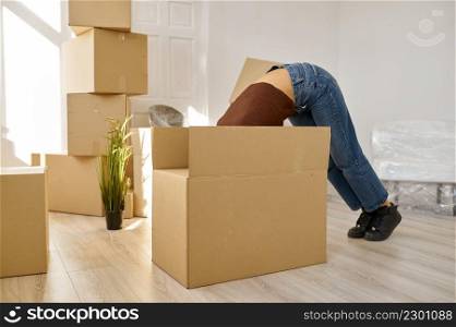 Funny woman looking something in big box partly hiding in it. Home moving. Girl in new flat. Funny woman looking something in big box