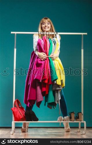 Funny woman taking all clothes in mall or wardrobe. Funny happy woman girl taking grabbing all clothes coats and shirts in wardrobe. Young girl shopping in mall. Fashion clothing sale concept.