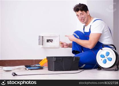 Funny young electrician working on socket at home