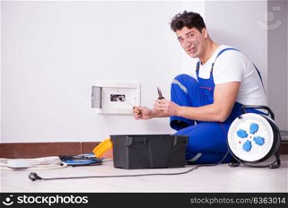 Funny young electrician working on socket at home