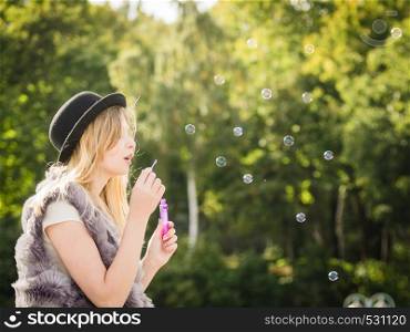 Funny young fashionable hipster teenage woman blowing soap bubbles outdoor having fun.. Joyful teen woman blowing bubbles
