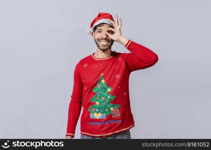 Funny young man in christmas hat looking through fingers. Funny christmas guy making gesture and looking through fingers, Man in christmas hat making gesture looking through fingers
