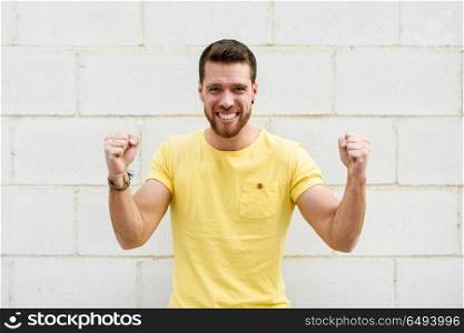 Funny young man on brick wall with funny expression.. Funny young man on brick wall with funny expression. Guy with winner gesture.