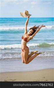 Funny young woman with beautiful body in swimwear jumping on a tropical beach.. Young woman with beautiful body in swimwear jumping on a tropical beach.