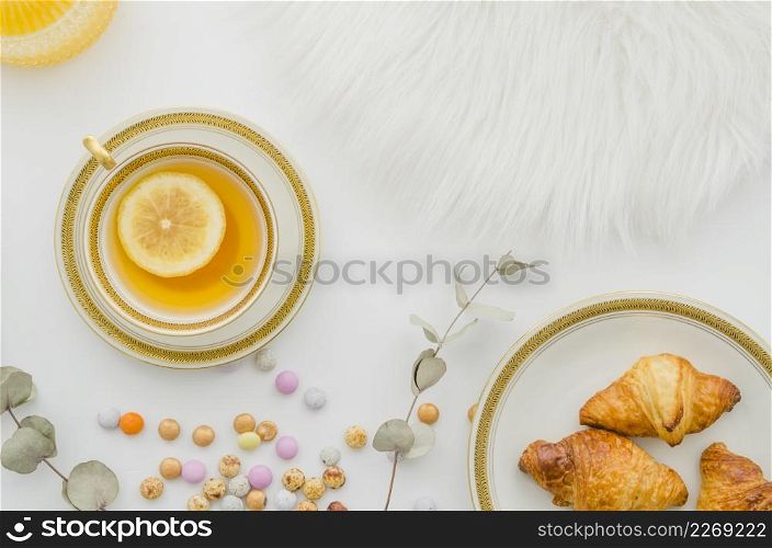 fur baked croissant candies ginger lemon tea cup white background