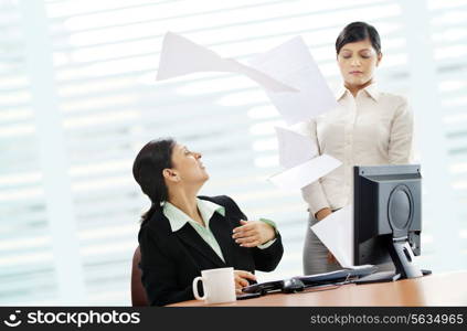 Furious mature businesswoman throwing papers on female executive