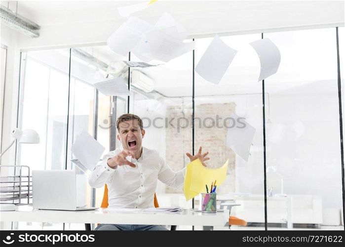 Furious mid adult businessman throwing documents in office