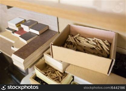 furniture production, manufacture and woodworking industry concept - wood dowel pins and board samples at workshop. wood dowel pins and board samples at workshop