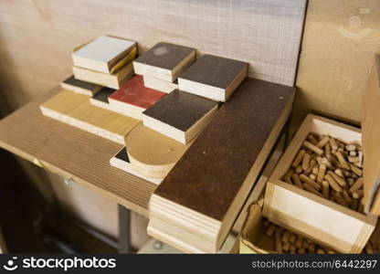 furniture production, manufacture and woodworking industry concept - wood dowel pins and board samples at workshop. wood dowel pins and board samples at workshop