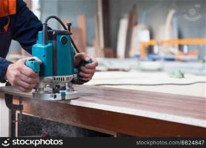 Furniture production or craft concept: worker polishing the wood surface of furniture part with polish machine. Furniture production concept