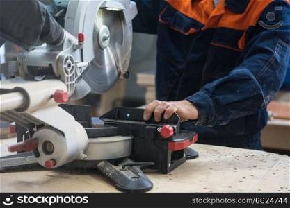 Furniture production or craft concept: worker sawing the wood surface of furniture part with saw machine. Furniture production concept