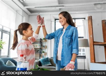 furniture renovation, diy and home improvement concept - happy smiling mother and daughter with sanding sponge and old wooden table making high five gesture at home. mother and daughter making high five gesture