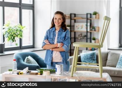 furniture restoration, diy and home improvement concept - happy smiling woman in gloves with crossed arms renovating old chair. happy woman with crossed arms renovating old chair