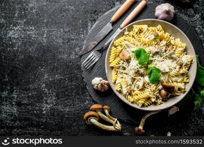 Fusilli pasta in a bowl of mushrooms and garlic. On rustic background. Fusilli pasta in a bowl of mushrooms and garlic.