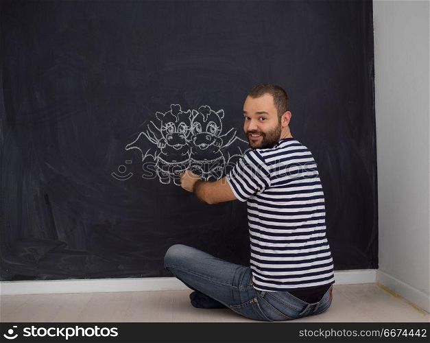 future dad drawing his imaginations on chalk board. Conceptual photo of future dad drawing his imaginations about the future life with children on chalk board
