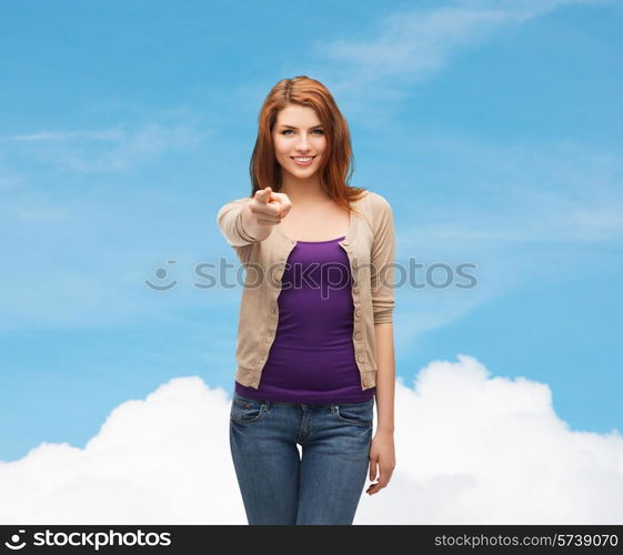 future, dream, gesture and people concept - smiling teenage girl in casual clothes pointing finger on you over blue sky and cloud background