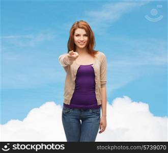future, dream, gesture and people concept - smiling teenage girl in casual clothes pointing finger on you over blue sky and cloud background