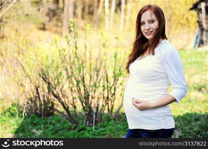 Future mom near verdant currant bushes on forest background