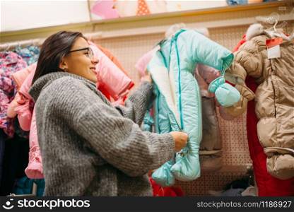 Future mother in the store for newborns, cloth department. Pregnant woman in the shop of goods for infants. Future mother in the store for newborns, cloth