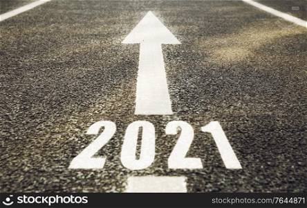 future, new beginning and destination concept - white road marking in shape of 2021 year and arrow. white road marking in shape of 2021 year and arrow