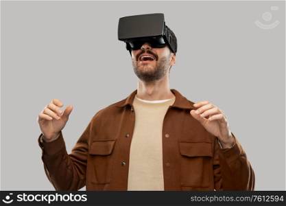 future, technology and people concept - happy smiling young man with mustaches in virtual reality headset or vr glasses over grey background. happy smiling young man in vr glasses