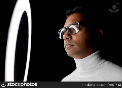 future technology, augmented reality and vision concept - indian man in glasses at white illumination over black background. man in glasses at white illumination over black