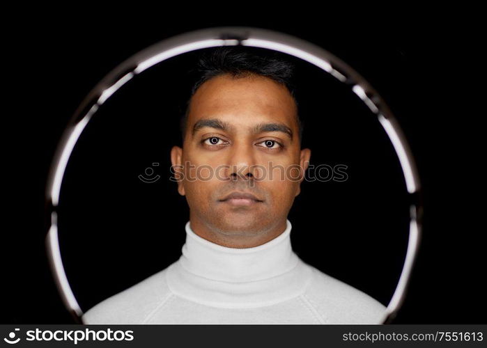 future technology concept - indian man over white illumination on black background. man in glasses over white illumination on black