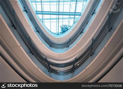 Futuristic architecture with a glass ceiling and spiral railings in a modern shopping center, with bright blue light, in Stuttgart city, Germany.