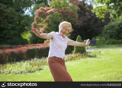 Gaiety. Delighted Playful Mature Woman with Outstretched Arms Laughing Outside