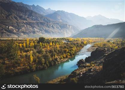 Gakuch in autumn show river flow through colorful forest and surrounded by mountains in Hindu Kush range. Ghizer, Gilgit-Baltistan, Pakistan.