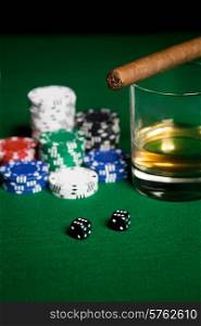 gambling, fortune and entertainment concept - close up of casino chips, whisky glass, dice and cigar on green table surface