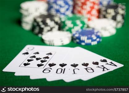 gambling, fortune, game and entertainment concept - close up of casino chips and playing cards on green table surface