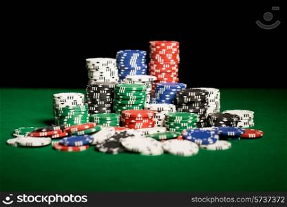 gambling, fortune, game and entertainment concept - close up of casino chips on green table surface