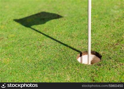 game, entertainment, sport and leisure concept - close up of flag mark in hole on golf field